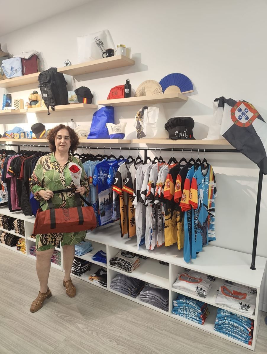 Mujer en una tienda sosteniendo una bolsa, de pie junto a estantes de ropa y mercancías.