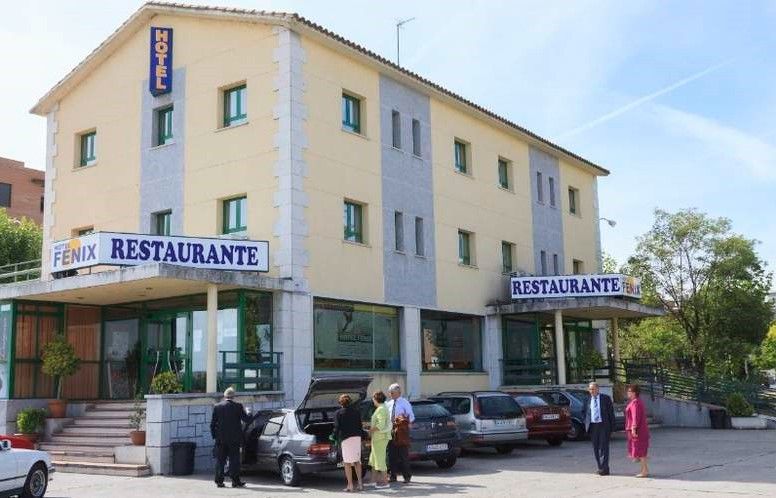 Hotel Fénix con restaurante, edificio de varias plantas. Gente cerca de coches; fachada azul y canela.