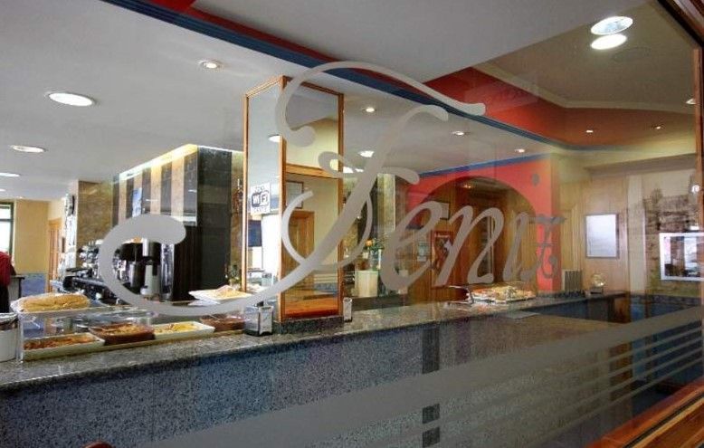 Interior de cafetería con barra, pasteles y una puerta de cristal con la palabra