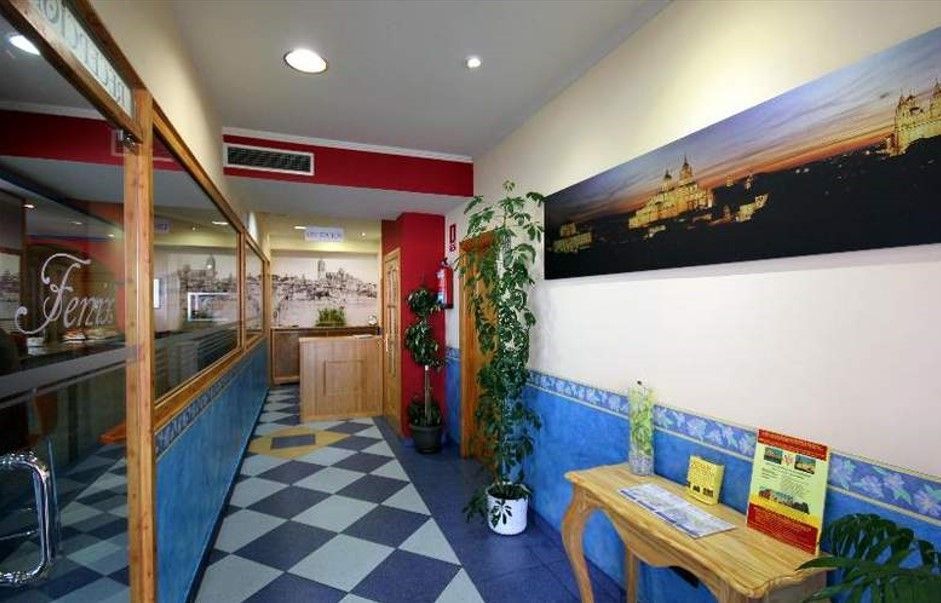 Pasillo con suelo de cuadros, paredes de azulejos azules y blancos y obras de arte. Un escritorio de madera con folletos.