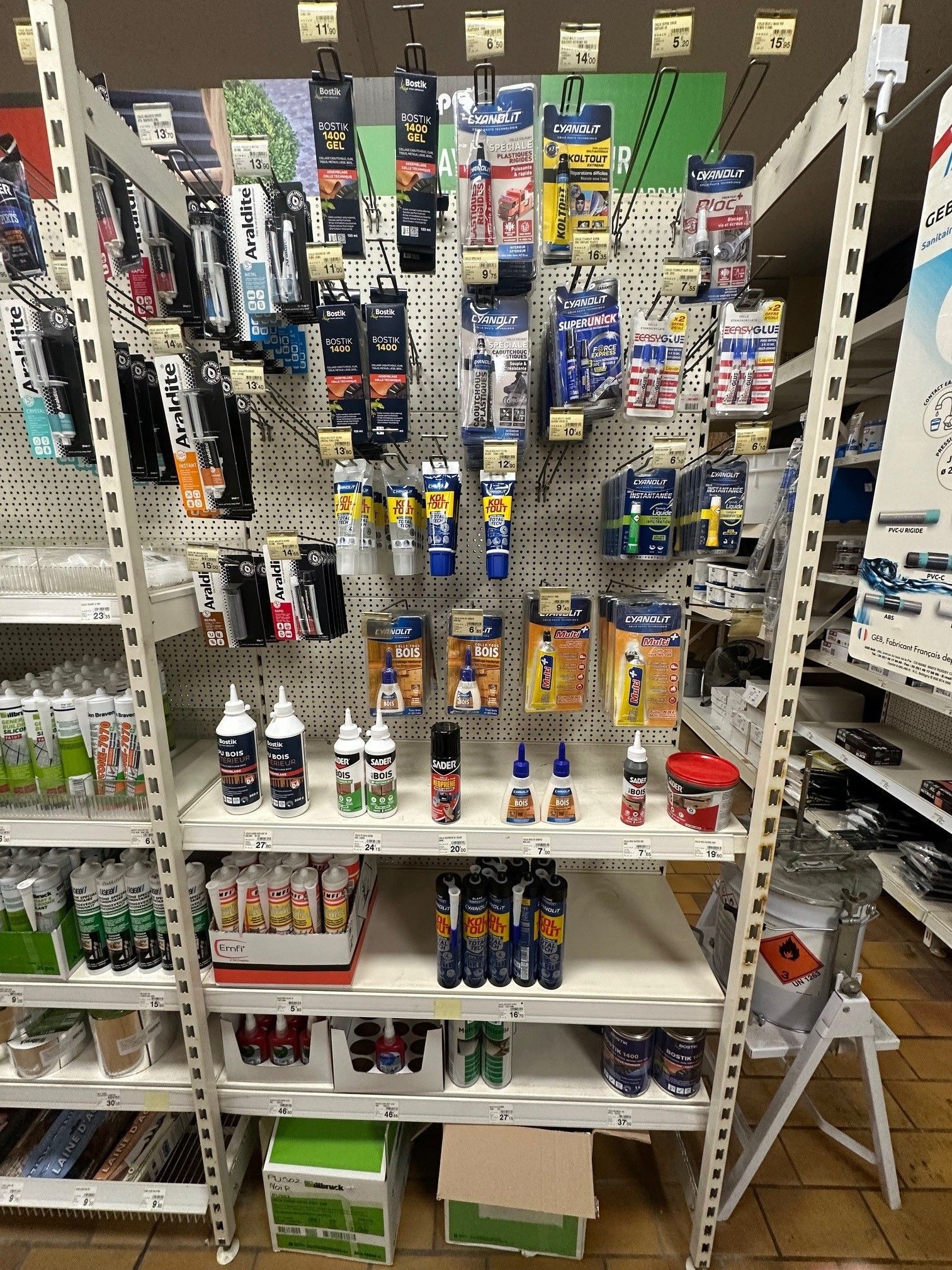 Rayonnage rempli de colles et d'adhésifs divers dans un magasin.