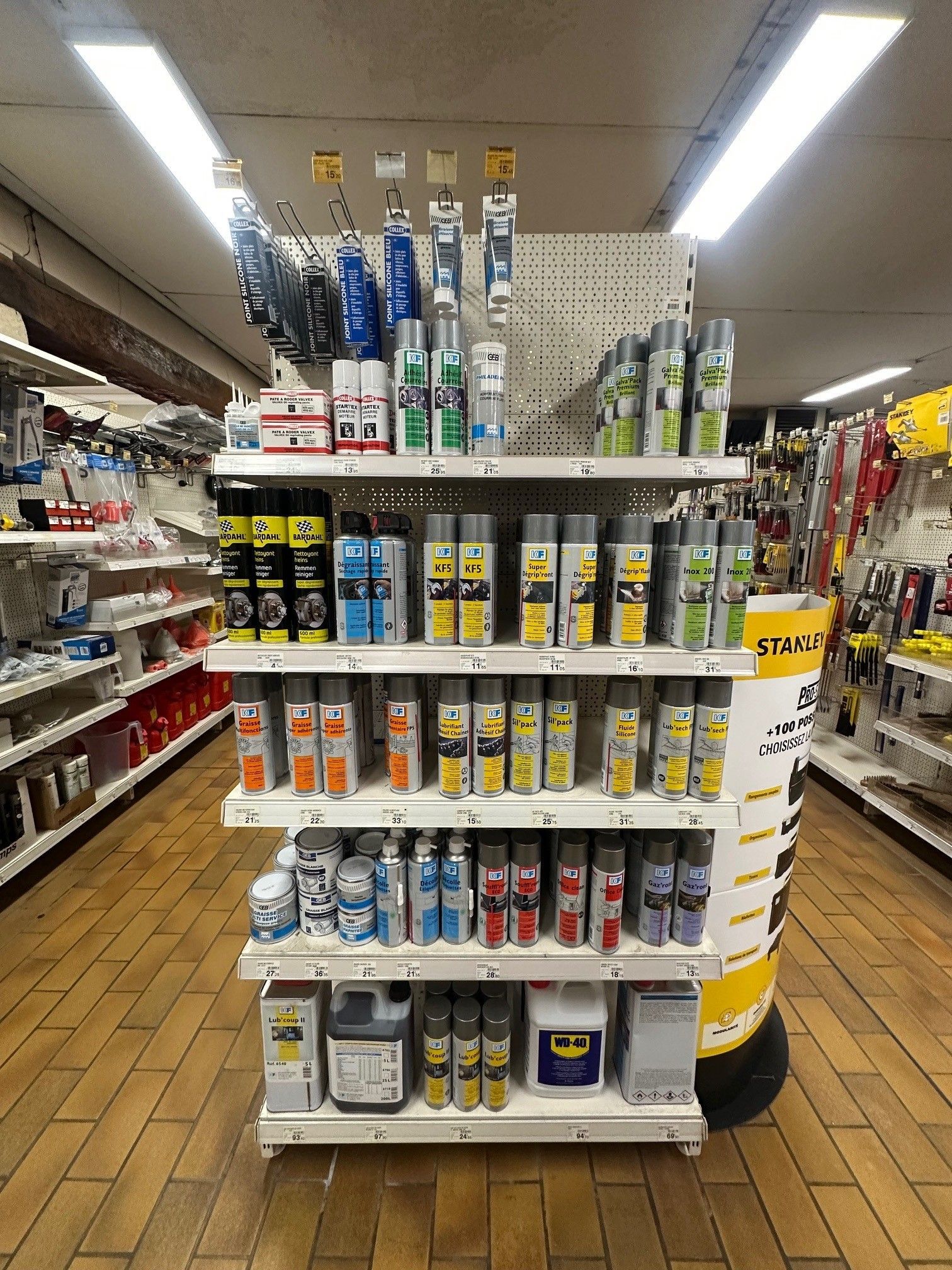 Présentoir d'allée dans une quincaillerie mettant en valeur divers produits dans des emballages colorés.