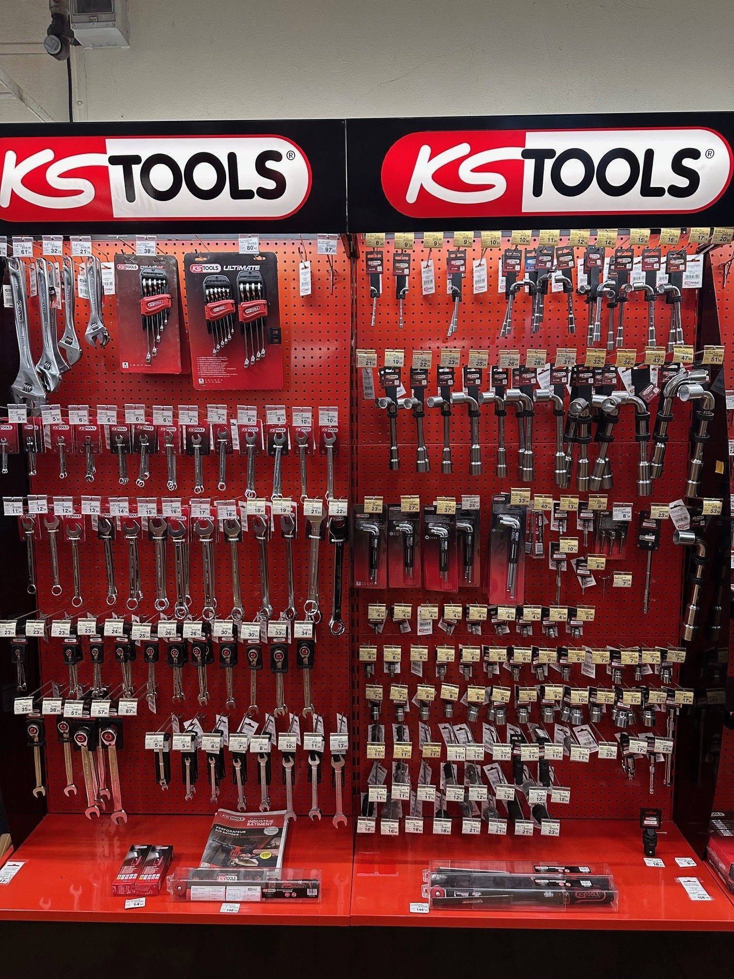 Présentoir à outils de marque KS TOOLS. Clés, cliquets et douilles sont suspendus à un panneau perforé dans un espace de vente.