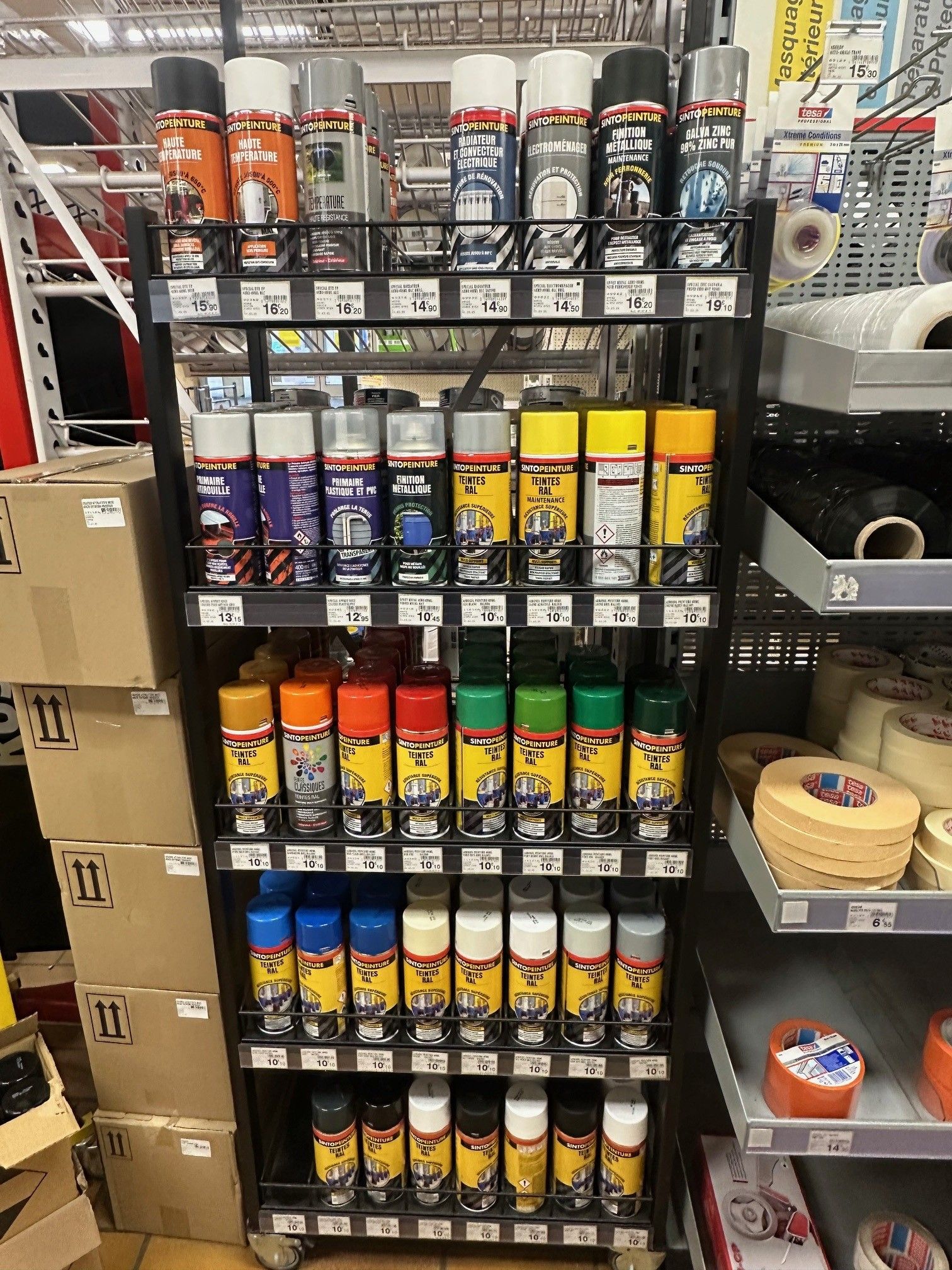 Présentoir métallique rempli de bombes de peinture de différentes couleurs. Exposé dans une quincaillerie.