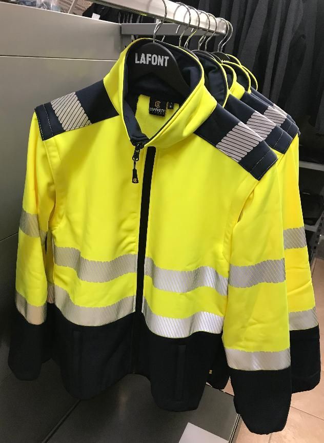Des gilets de sécurité jaunes et noirs à bandes réfléchissantes sont suspendus à un portant.