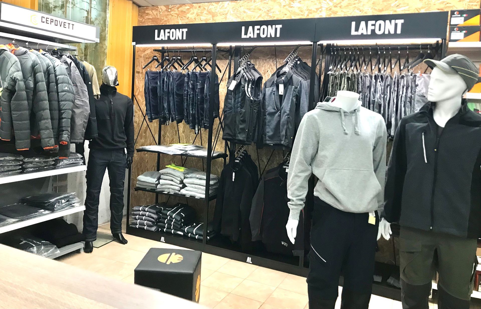 Intérieur d'un magasin de vêtements présentant des vestes, des pantalons et des chemises sur des portants et des mannequins ; enseigne LAFONT visible.