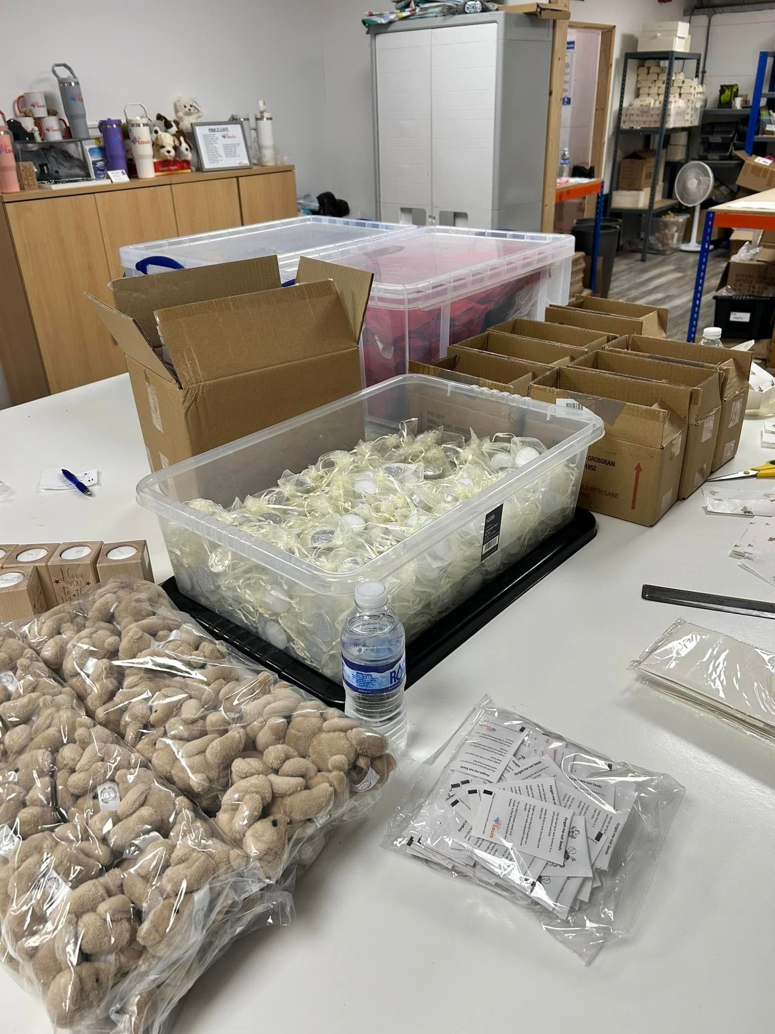 A table filled with lots of boxes , containers , and a bottle of water.