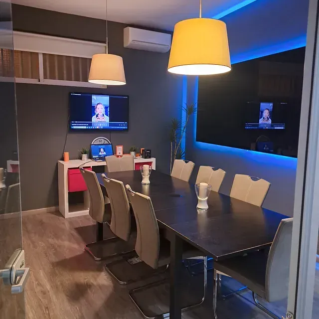 Una sala de conferencias con mesa, sillas y un televisor de pantalla plana.