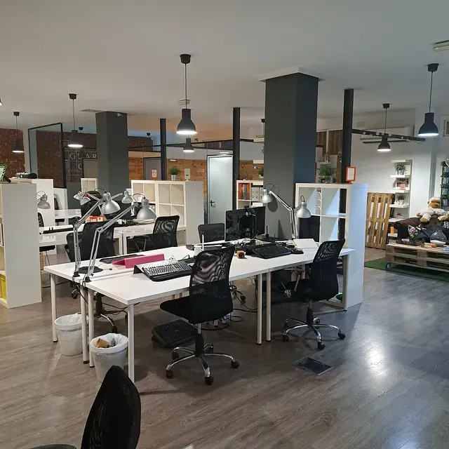 Una oficina grande con muchos escritorios y sillas.