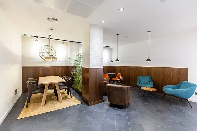 Una sala de estar con una mesa y sillas y un reloj en la pared.