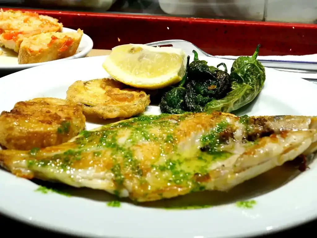 Copa de vino junto a varios quesos, pan y un cuchillo de queso sobre una tabla de madera.