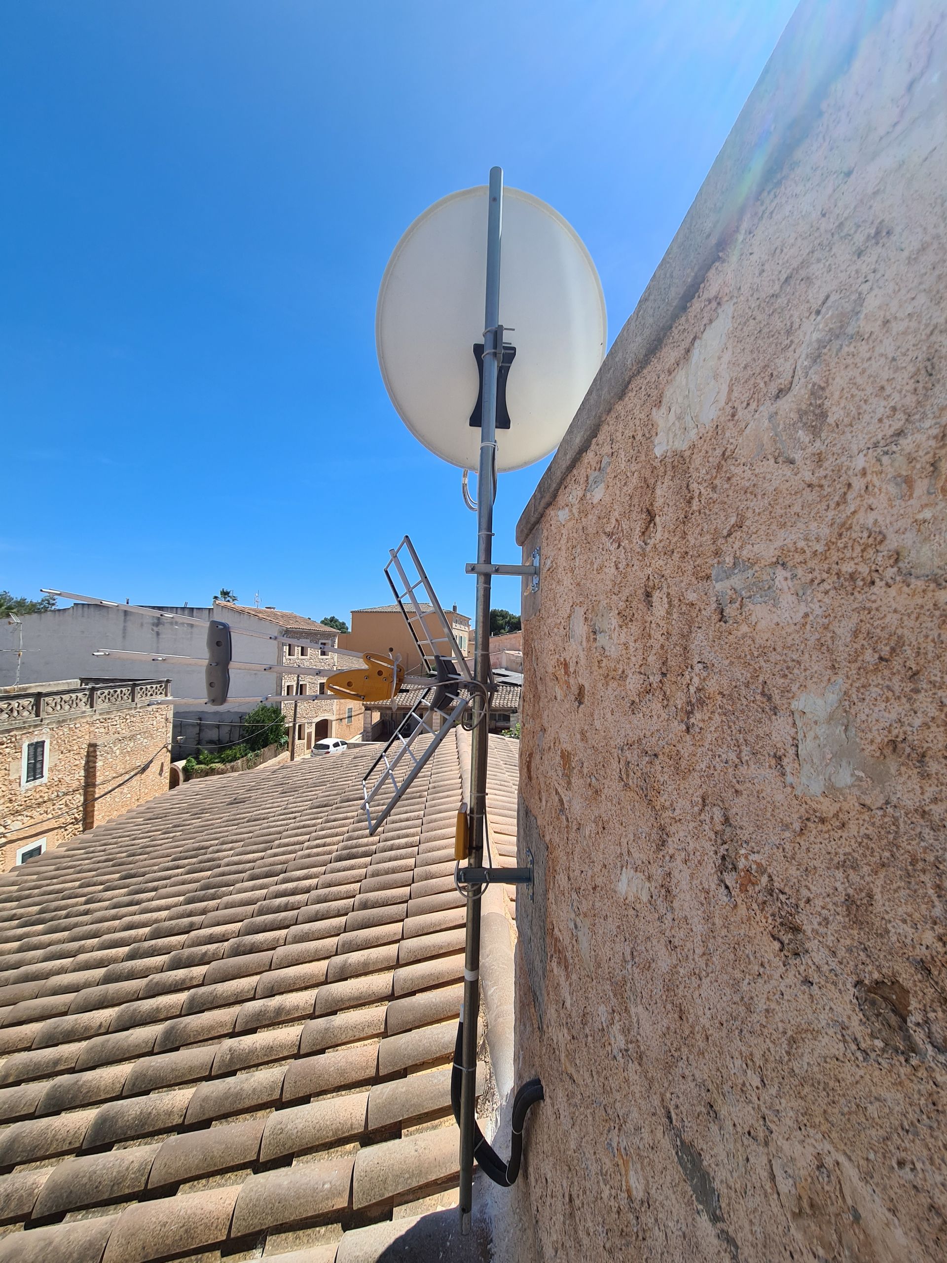 Una antena parabólica está fijada al costado de un edificio.