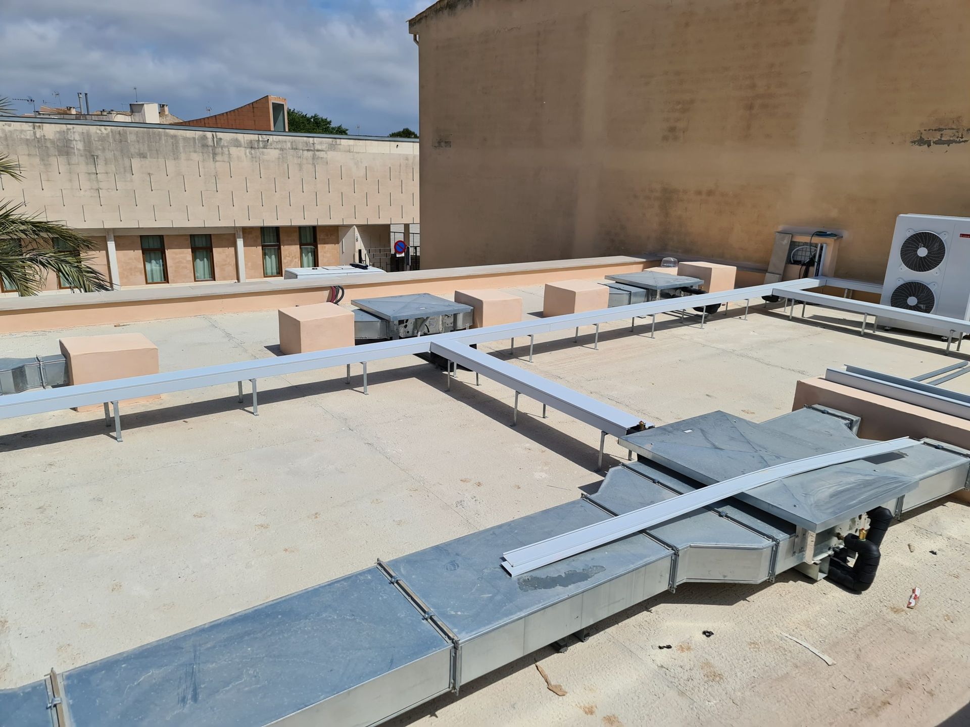 Un tejado con muchos conductos y un edificio al fondo.