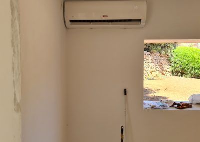 Una habitación con una ventana y un aire acondicionado en la pared.