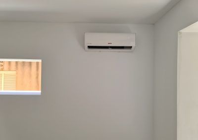 Una habitación con una ventana y un aire acondicionado montado en la pared.