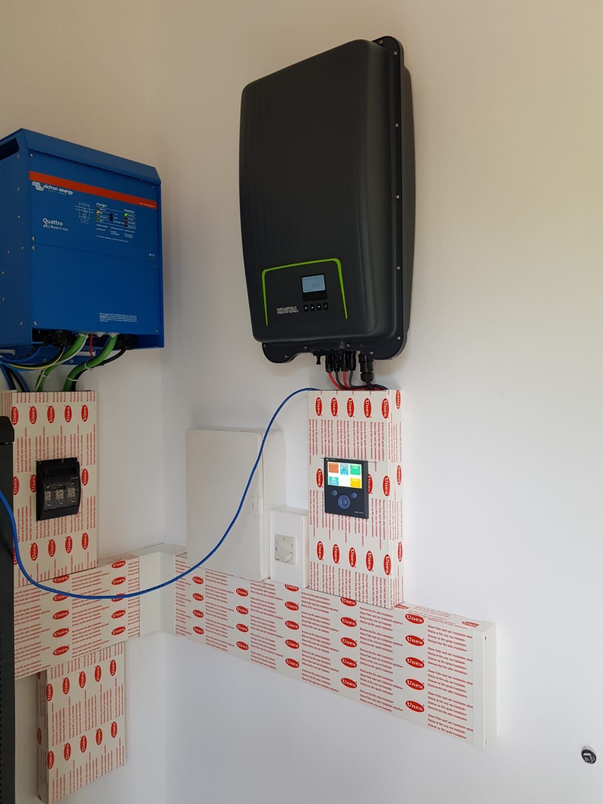 Un panel solar está montado en una pared al lado de una batería azul.