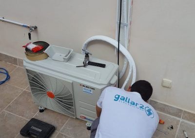Un hombre que viste una camiseta de Gallar 2 está trabajando en un aire acondicionado.