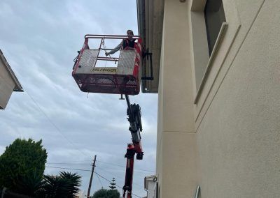 Un hombre está sentado en un cubo encima de una grúa.