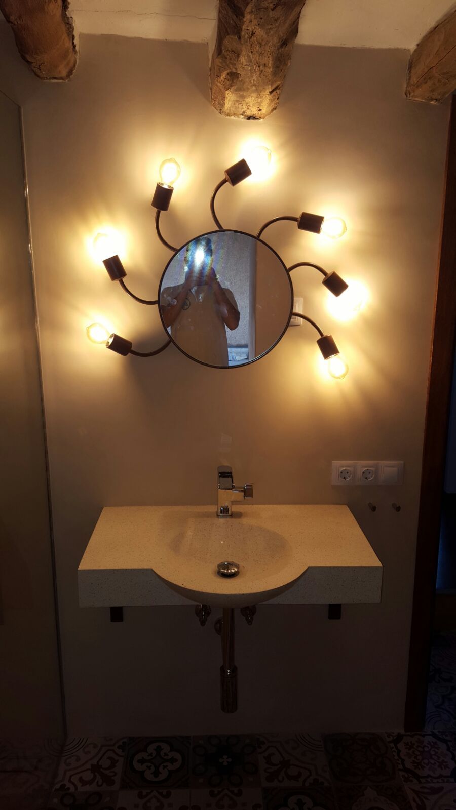 Un lavabo de baño con espejo y luces en la pared.