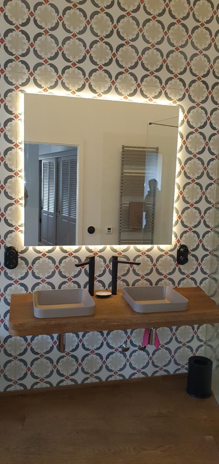 Un baño con dos lavabos y un espejo con luces.