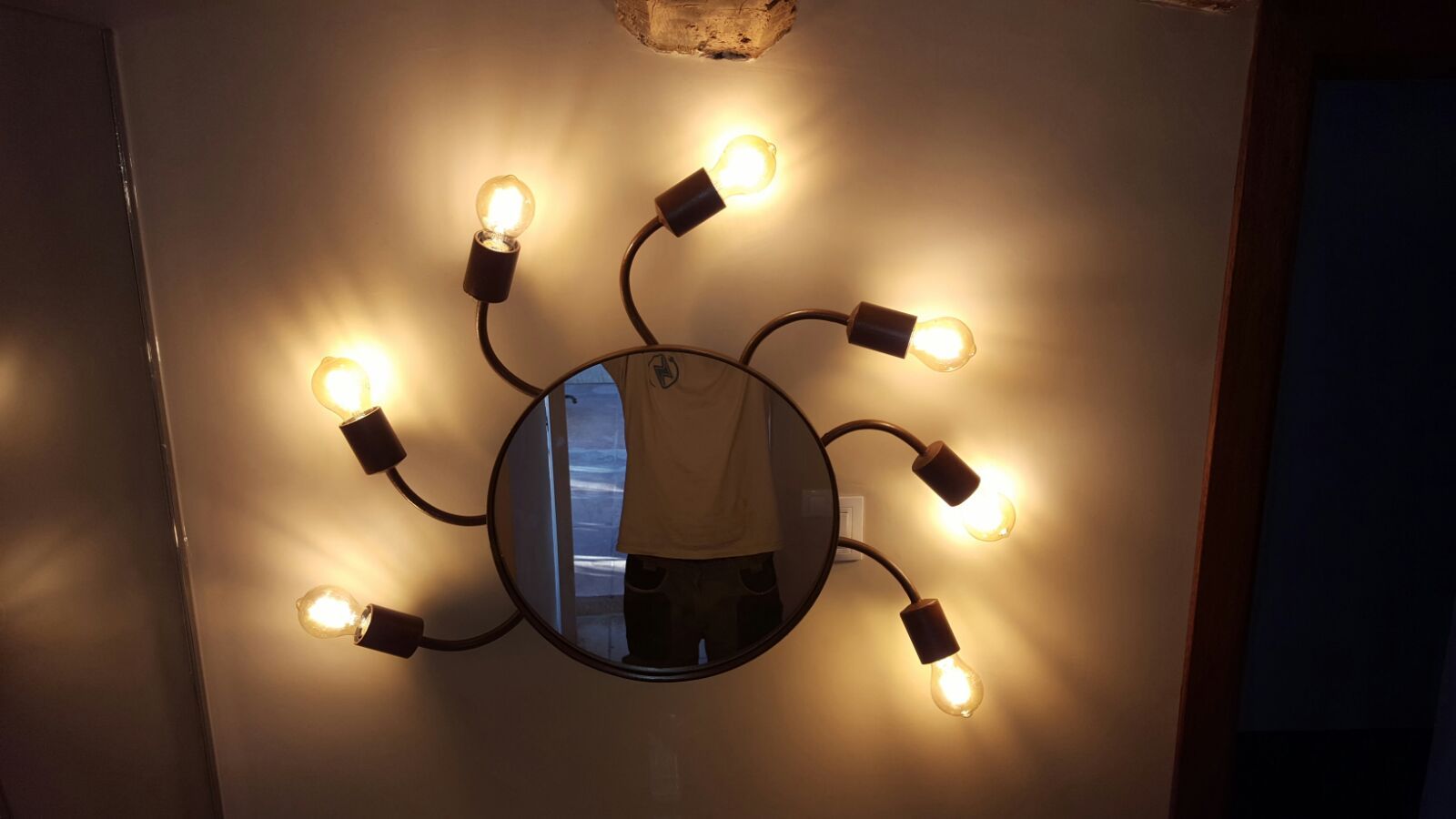 Una persona está parada frente a un espejo con luces.