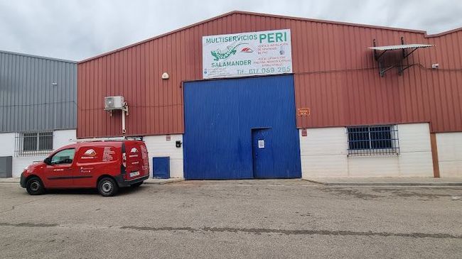 Una camioneta roja está estacionada frente a un edificio con una puerta azul.