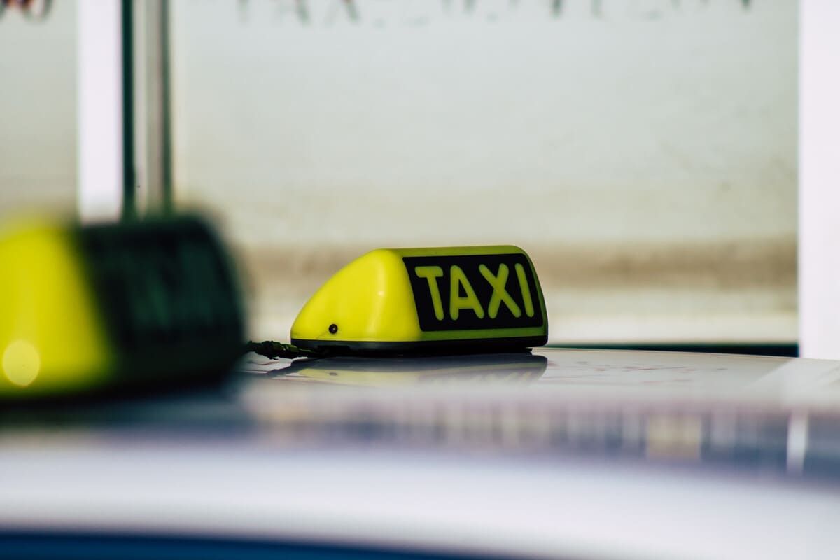 Letrero de taxi amarillo encima de un coche con la palabra 