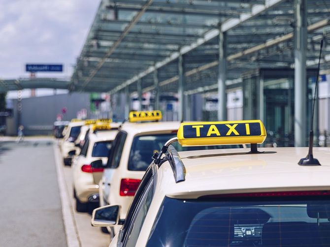 Taxis estacionados en fila en un centro de transporte con carteles de