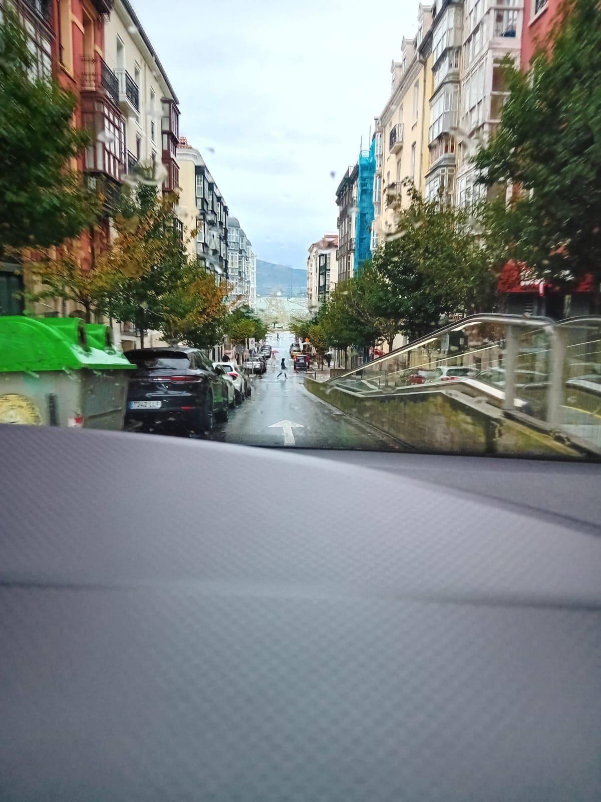 Escena callejera en Bilbao, España; edificios bordean una carretera que conduce a un puente en la distancia.