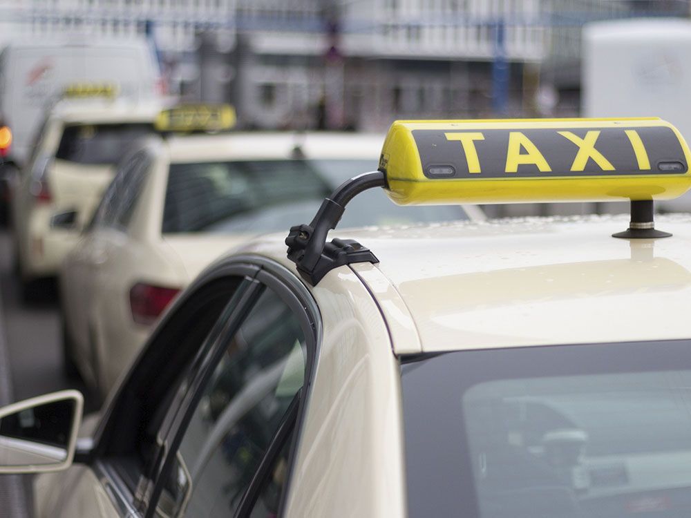 Letrero de taxi amarillo en el techo, autos alineados, calle de la ciudad.