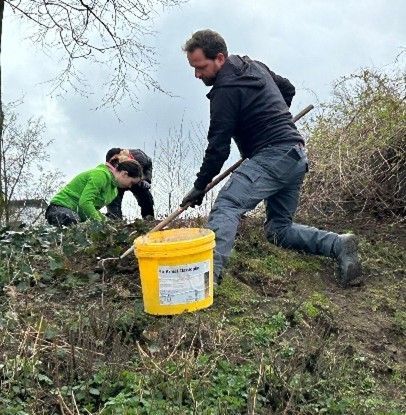 Ein Mann kniet neben einem gelben Eimer auf einem Feld.