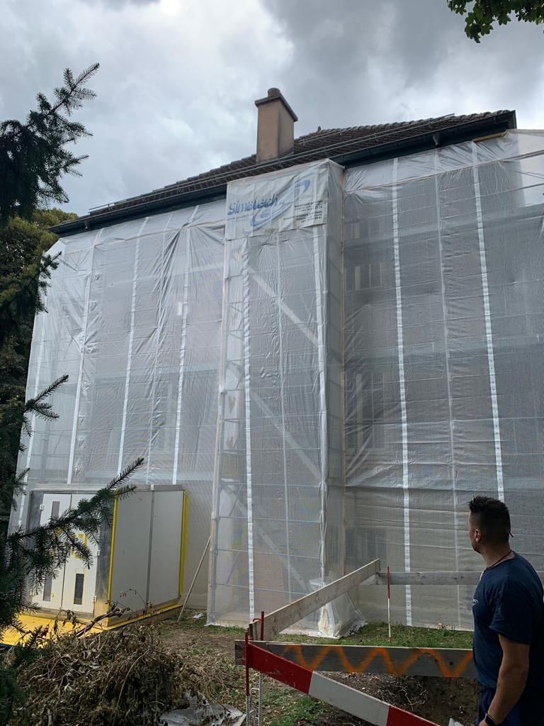 Un homme se tient devant un bâtiment recouvert d'échafaudages.