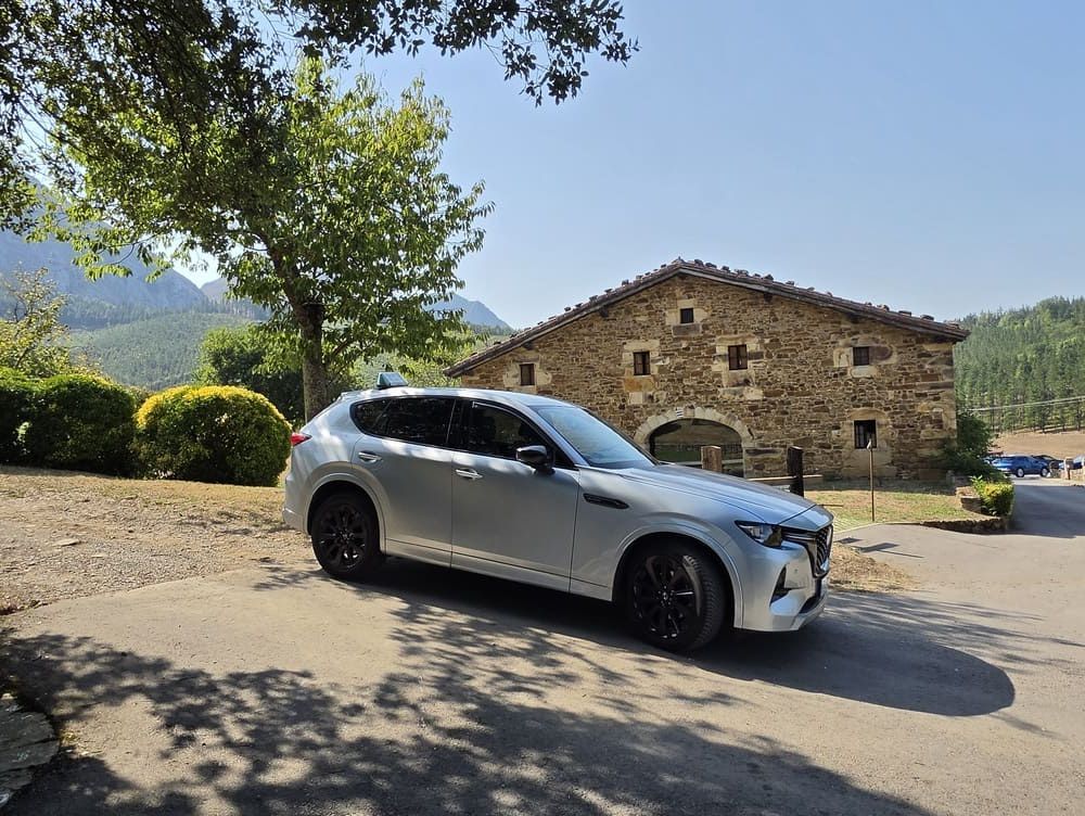 Un SUV plateado estacionado junto a un edificio de piedra en un paisaje rural soleado.
