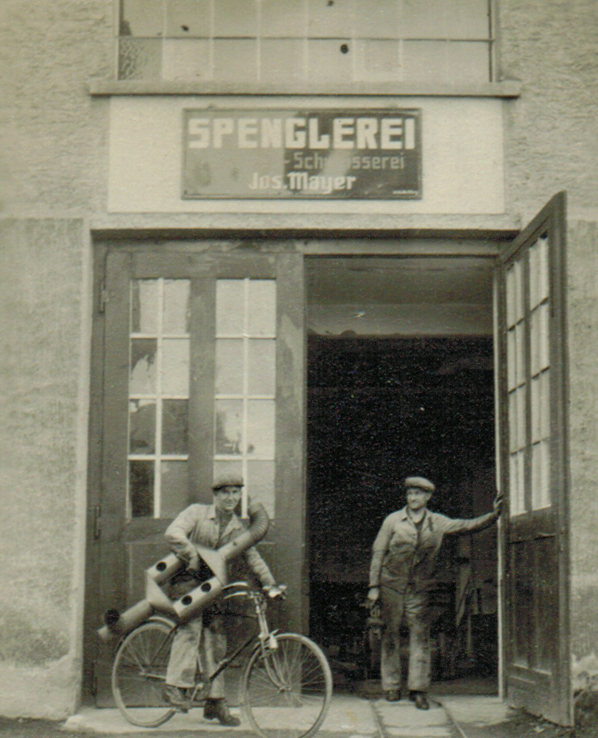 Zwei Männer stehen vor einem Geschäft namens Spenglerei