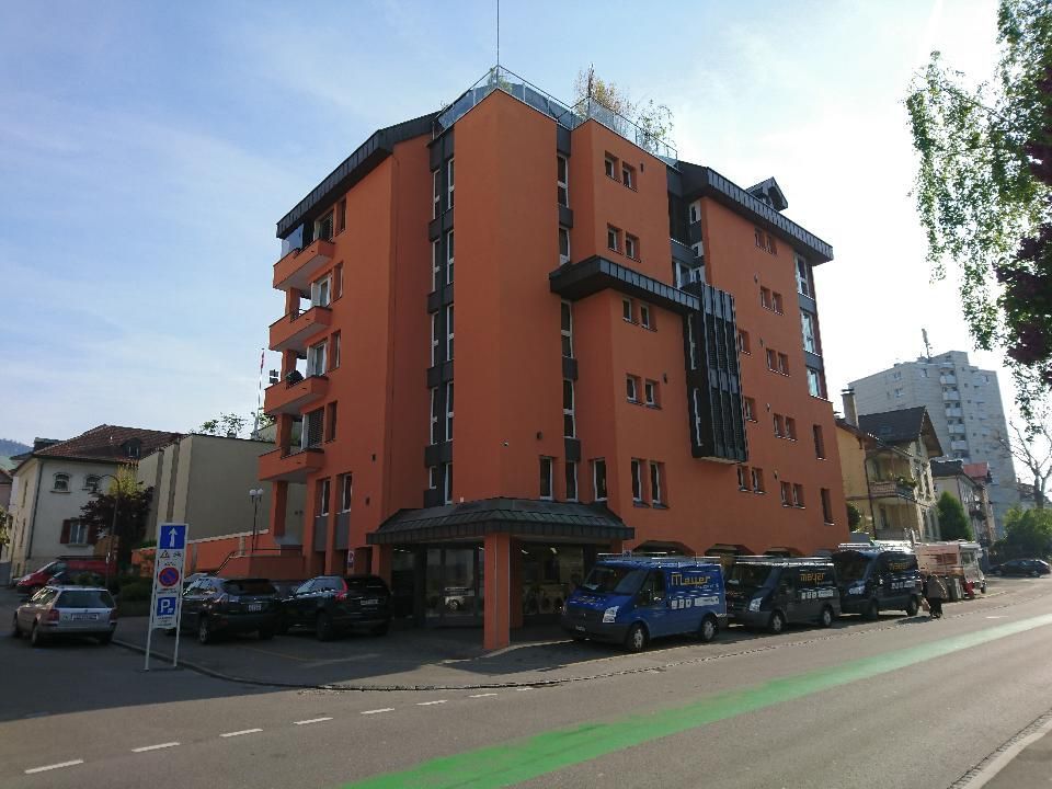 Ein großes orangefarbenes Gebäude mit davor geparkten Autos