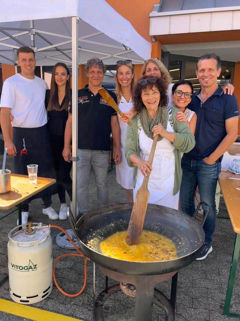 Eine Gruppe von Menschen steht um eine große Pfanne mit Essen herum