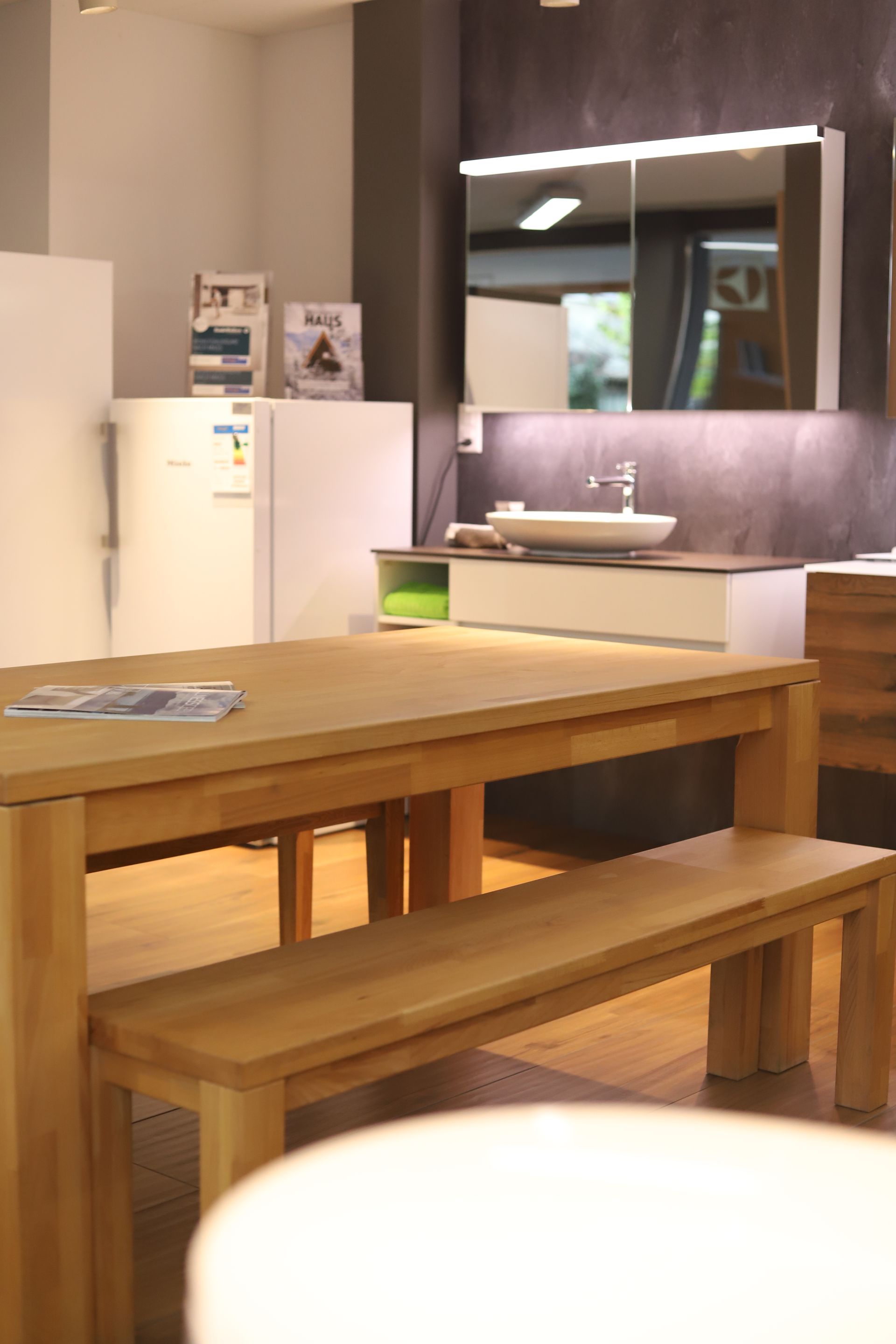 Ein Holztisch mit Bank in einem Raum mit Kühlschrank und Spüle