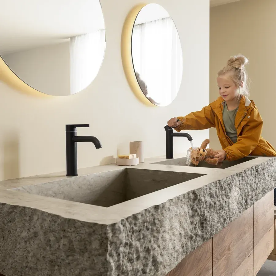 Ein kleines Mädchen wäscht ihre Hände in einem Waschbecken im Badezimmer