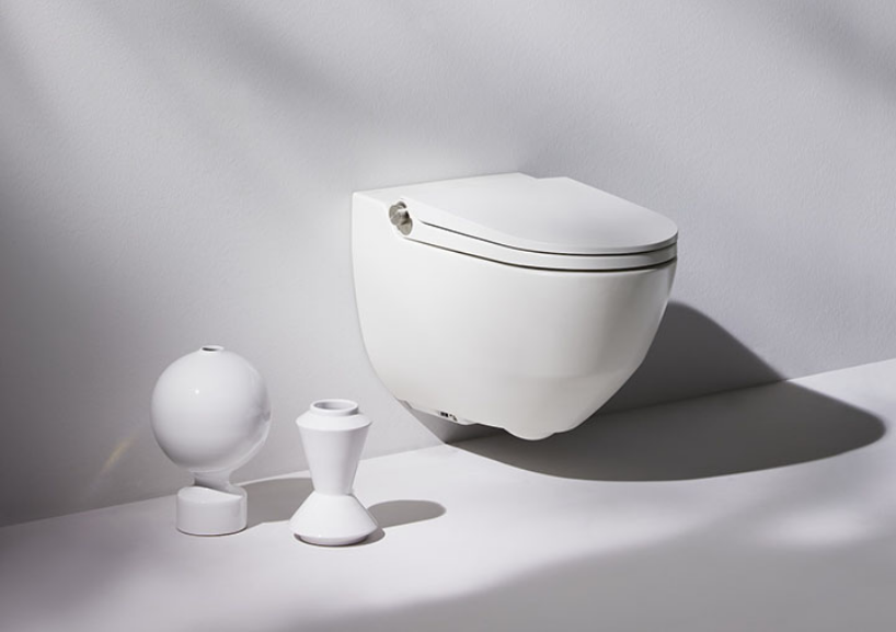 Eine weiße Toilette hängt neben zwei Vasen an der Wand.