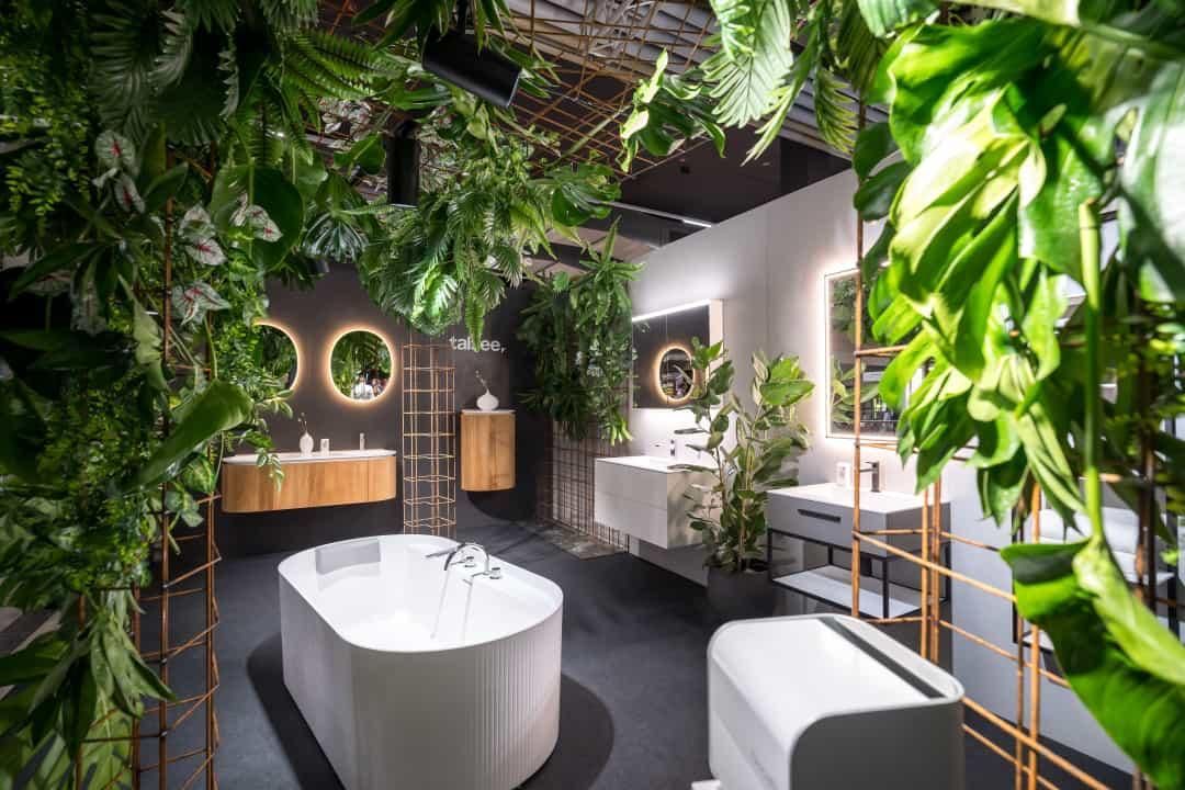 Ein Badezimmer mit Badewanne, Waschbecken, Spiegeln und von der Decke hängenden Pflanzen.
