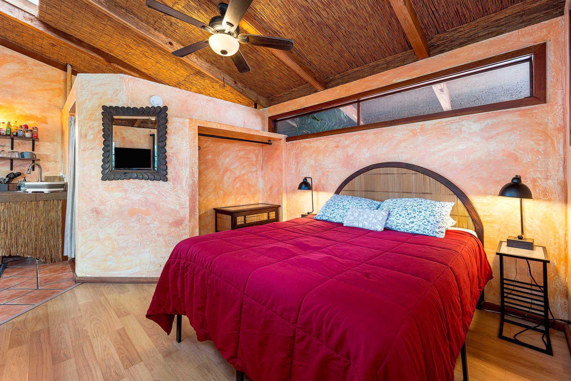 Bedroom with red bedding, wooden ceiling, and side tables.