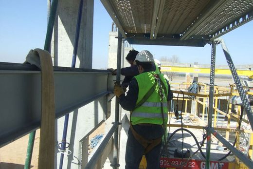 Un hombre que lleva un chaleco de seguridad está trabajando en una estructura metálica.