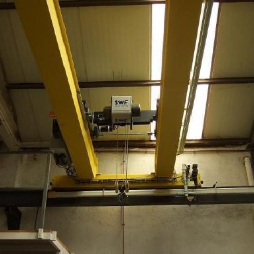 Una grúa amarilla cuelga del techo de un edificio.