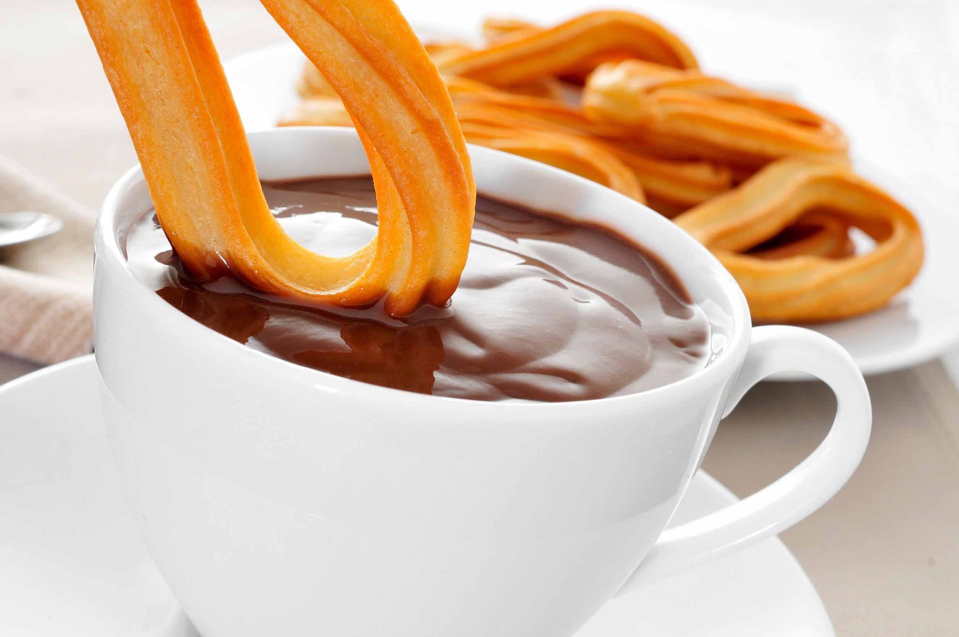Un churro sobresale de una taza de salsa de chocolate.