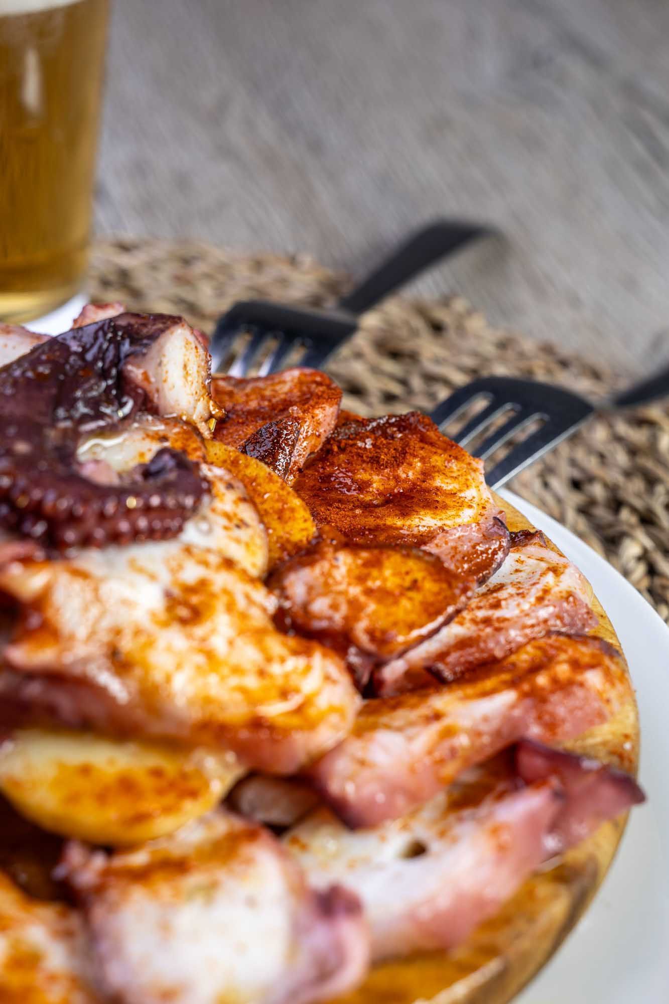 Un primer plano de un plato de comida con un vaso de cerveza en el fondo.