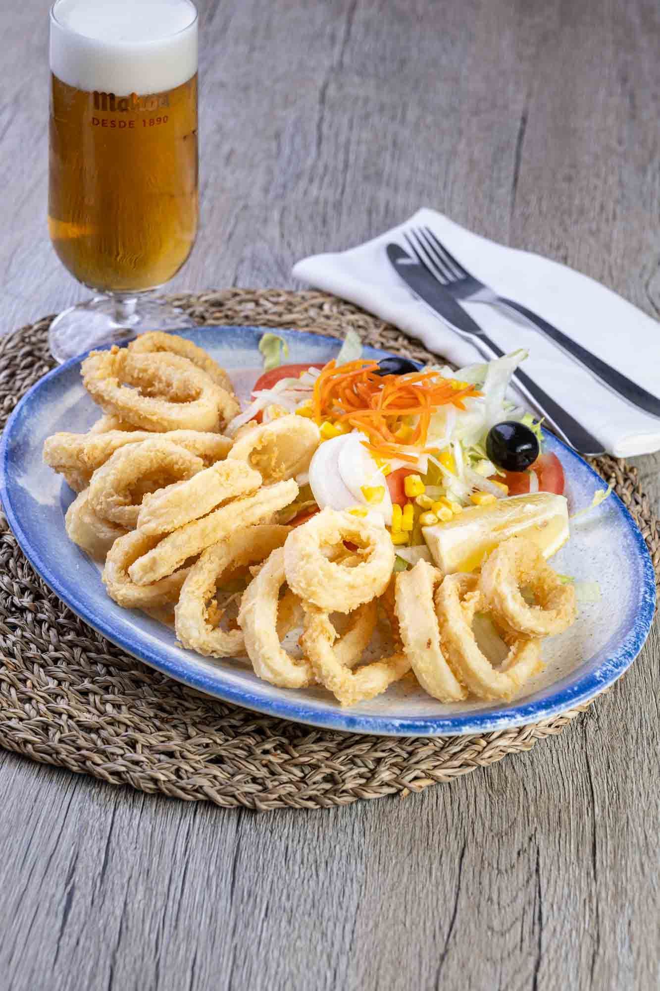 Un plato de comida con un vaso de cerveza en una mesa.
