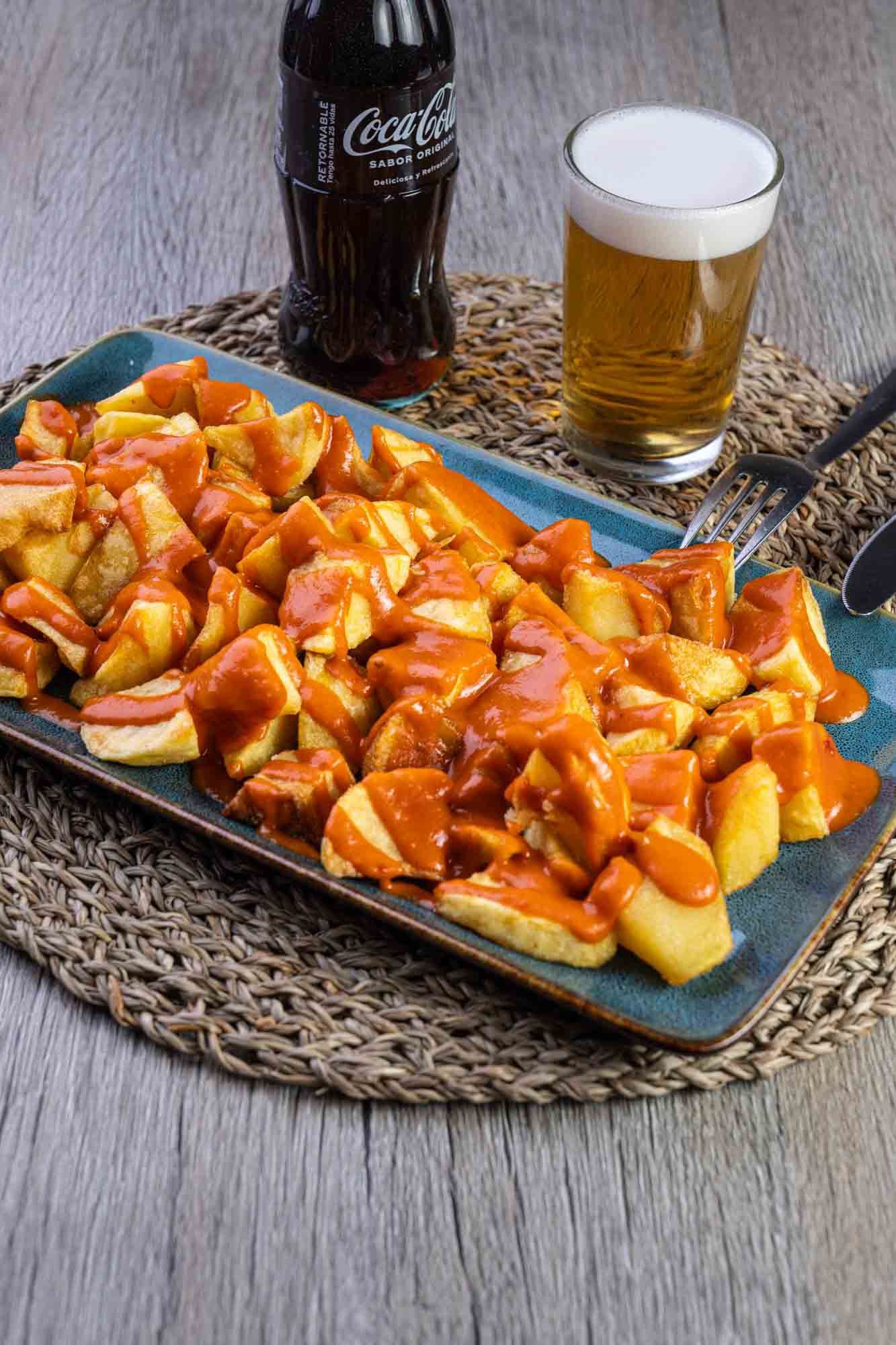 Un plato de comida con un vaso de cerveza y una botella de Coca Cola sobre una mesa.
