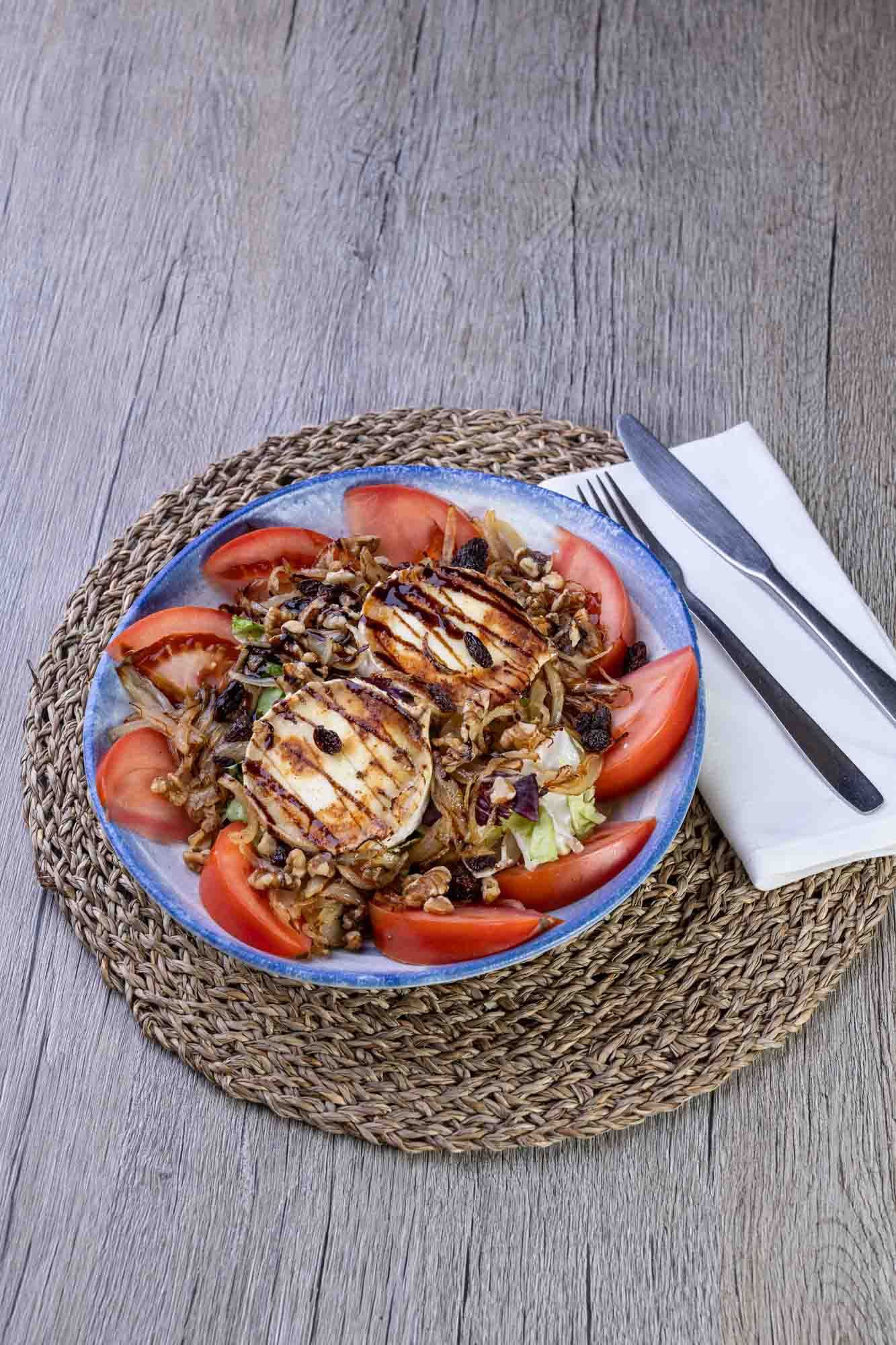 Un plato de comida con tomates y queso sobre un mantel sobre una mesa.