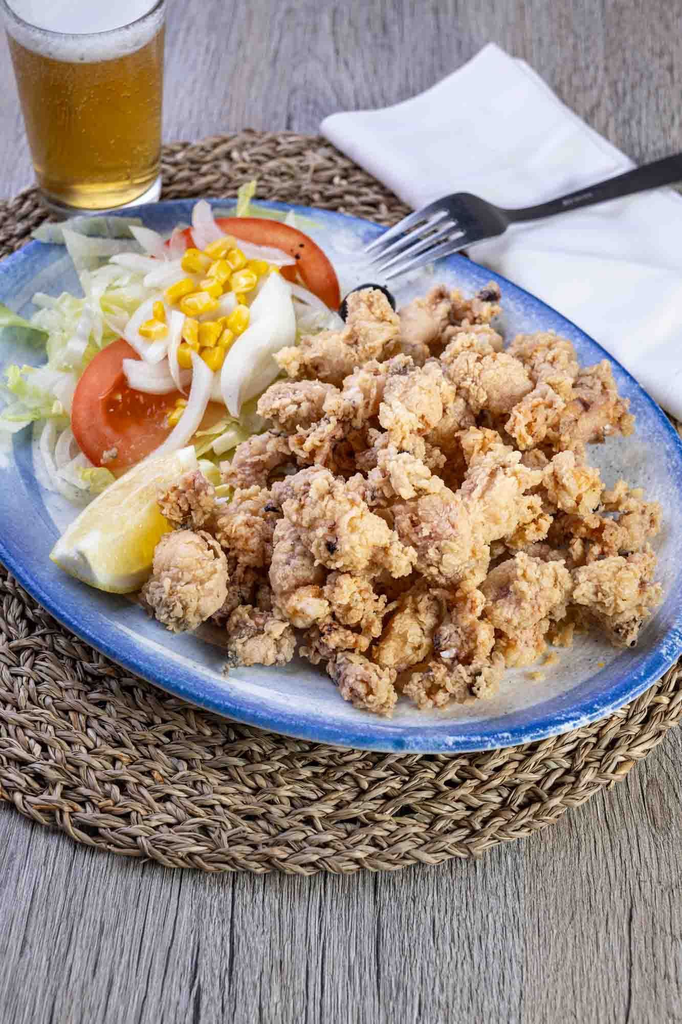 Un plato de comida con ensalada y un vaso de cerveza en una mesa.