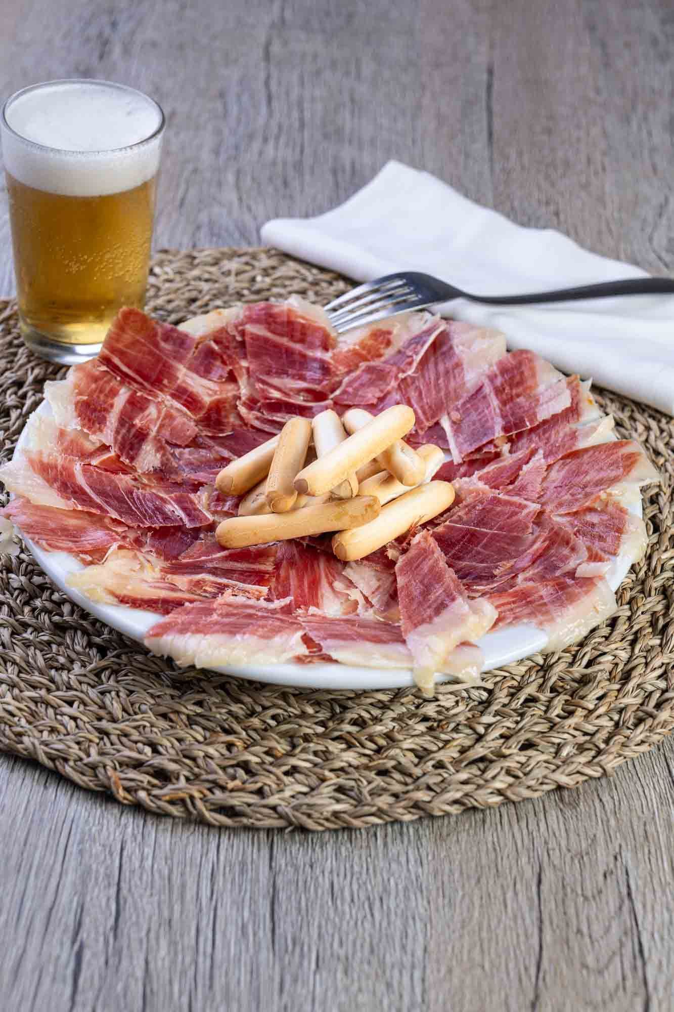 Un plato de carne y un vaso de cerveza sobre una mesa.